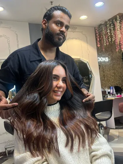 A happy client with her stylist, showing off her new balayage. The warm brown and caramel tones perfectly complement her complexion.