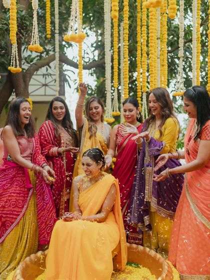 The bride's Haldi ceremony, surrounded by her friends and family. The decor features a canopy of hanging marigold and tuberose strings, creating a traditional and festive ambiance.