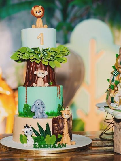 A close-up of the safari-themed cake for Eshaan's birthday, showcasing the detailed fondant animals like a monkey, elephant, and giraffe climbing the tiers.