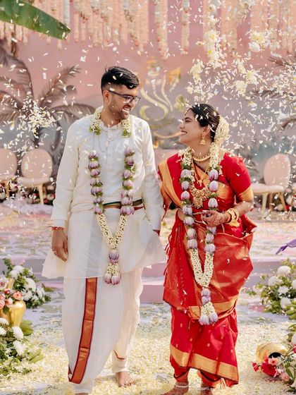 A happy moment from the South Indian wedding, with the couple showered in flower petals as they walk down the aisle.