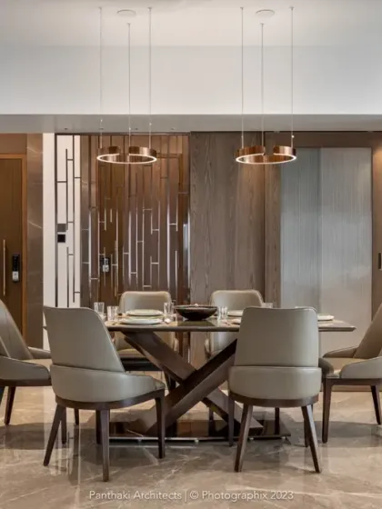 A thoughtfully curated dining area featuring a table with a unique cross-base design and elegant leather chairs. Wood-paneled walls and contemporary pendant lights add warmth and sophistication, creating an intimate atmosphere for meals.