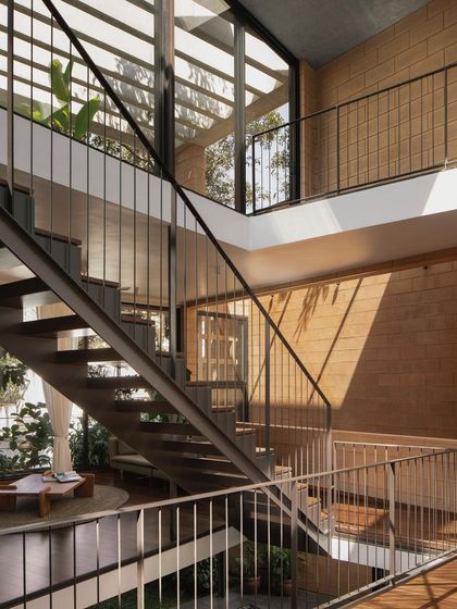 The open staircase at the Debris Block House connects multiple levels while maintaining visual connection and allowing light to permeate the interior. The design uses simple steel railings and warm wood treads.