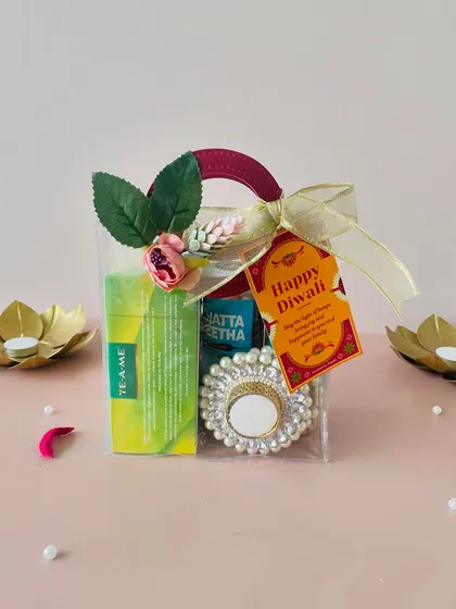 A cute and budget-friendly Diwali gift bag. This transparent bag with a handle holds tea, snacks, and a pearl T-light holder, finished with a "Happy Diwali" tag.