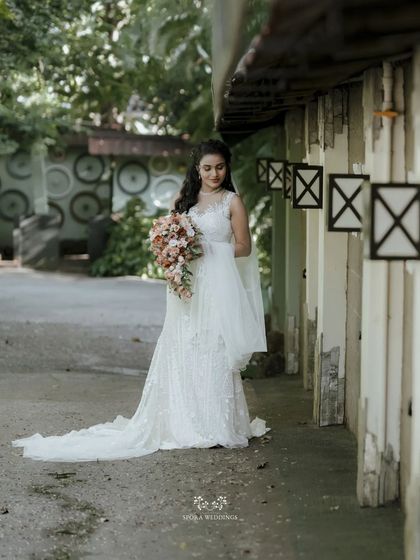 The bride stands elegantly in a covered walkway, her full gown and veil on display in this beautiful portrait.
