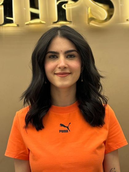 A smiling client with a fresh haircut and color. The shoulder-length style is modern and chic, enhanced by the deep, uniform color.