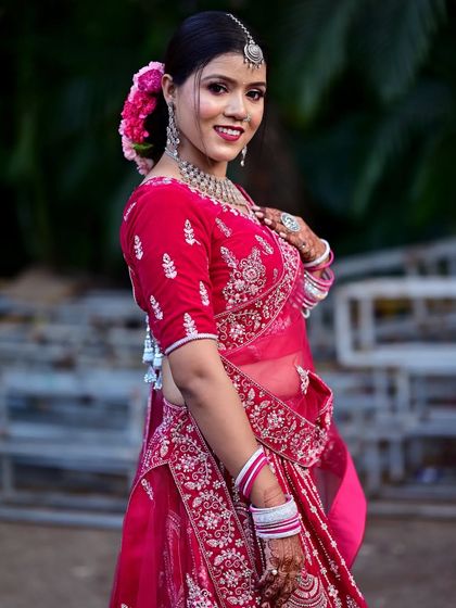 A side profile of the bride, highlighting the elegant hairstyle with a floral bun and the detailed embroidery on the blouse.