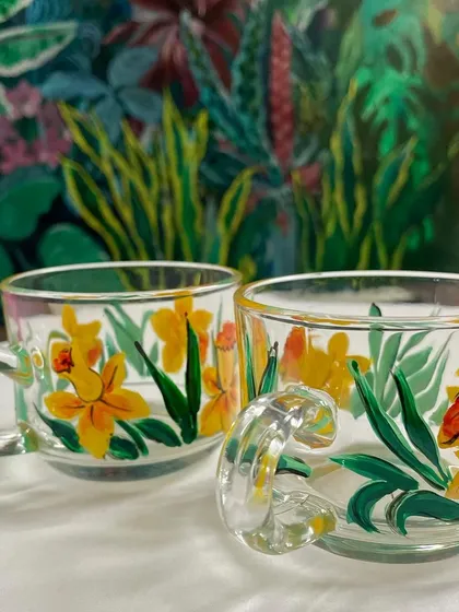 A pair of glass cups painted with bright yellow daffodils, bringing a touch of spring to your table.