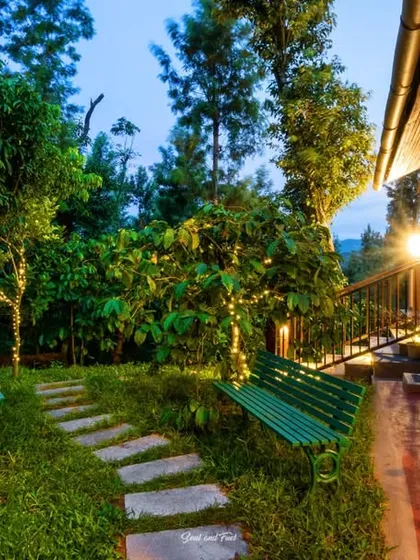A magical garden path at "Eorthe" in Coorg, with trees wrapped in fairy lights. The scene is enchanting and romantic, creating a perfect evening atmosphere at this beautiful homestay.