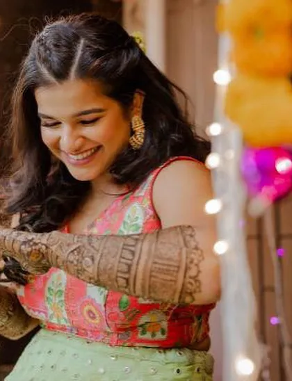 A candid moment from a Mehendi function. The makeup is fresh and vibrant, with a pop of pink on the eyes to match her outfit.