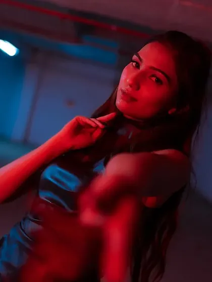 A captivating portrait with a shallow depth of field, drawing focus to the model's intense gaze amidst the colored lights.