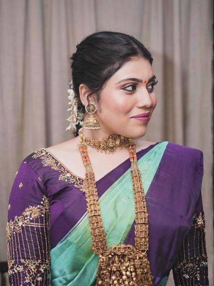 A three-quarter profile view that highlights the delicate hair accessories and the smooth application of the makeup. The look is clean, fresh, and beautiful.