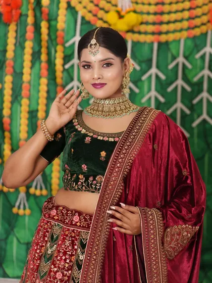 A beautiful model in a green and red lehenga, wearing a Kundan choker. This is a classic combination for any festive occasion.