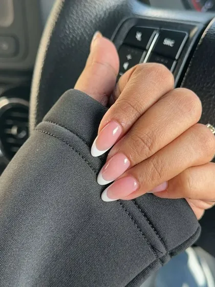 A casual shot of a perfectly executed French manicure on natural-looking oval nails, ideal for an everyday chic look.