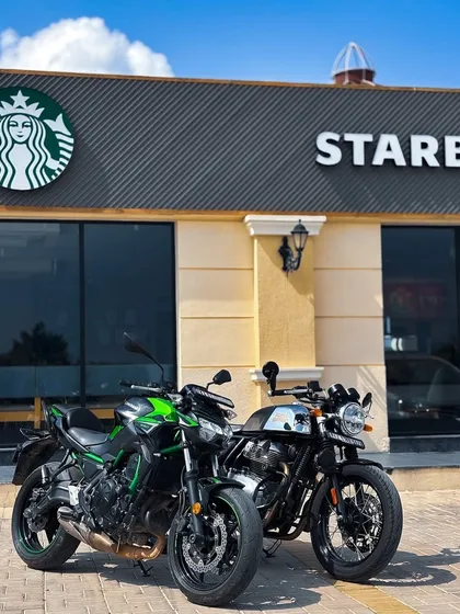 Two motorcycles, a Kawasaki and a Triumph, parked in front of Starbucks, showcasing a typical scene from a weekend ride and coffee break.