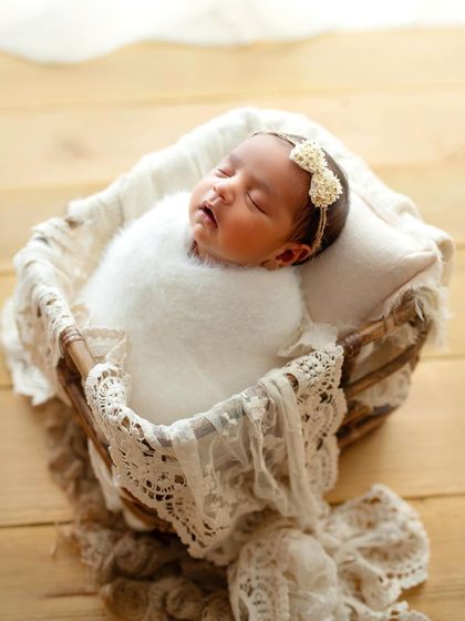 I love the simplicity of an all-white setup. This little one is wrapped in a soft, fluffy blanket in a lace-trimmed basket, looking pure and angelic.