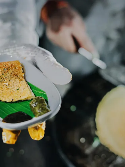 A mini dosa, perfectly crisp and golden, served fresh off the griddle. Paired with traditional chutneys on a banana leaf, it's a taste of South India that's always a crowd-pleaser at my events.