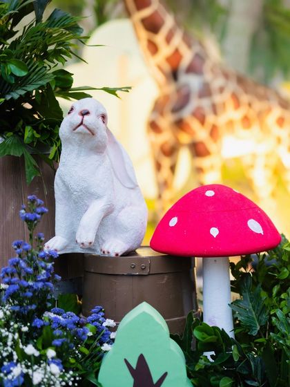Detail shot of a rabbit prop and a red mushroom, adding a touch of whimsy to the dense foliage of the safari theme.