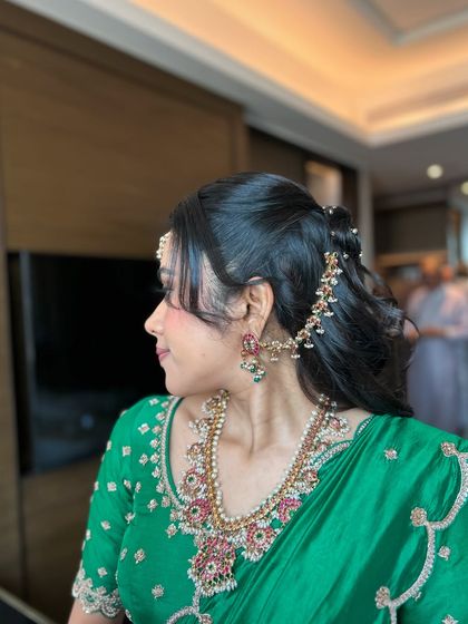 A trendy half-up, half-down style with a small bun and flowing curls, adorned with delicate ghungroo accessories for a touch of tradition.