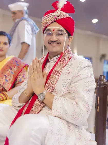 The groom sits during the wedding ceremony, his hands joined in a gesture of respect and prayer.