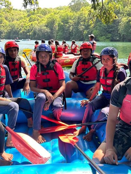 A team of campers gets ready for their rafting adventure, seated in the raft and awaiting instructions.