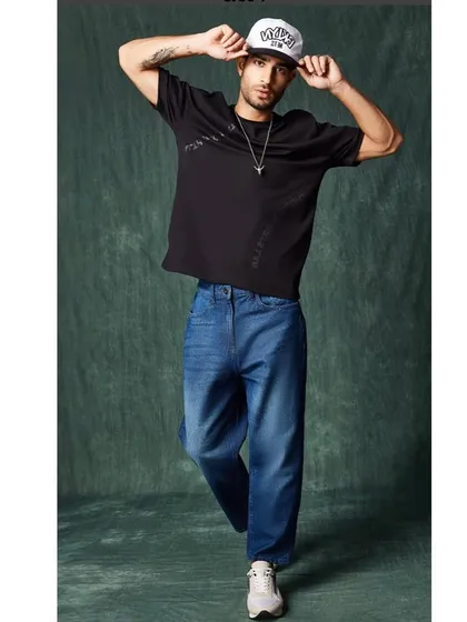 A full-length athleisure look, combining the oversized tee and cap with baggy jeans, capturing the essence of contemporary streetwear.