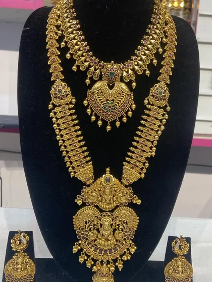 A beautiful example of a layered bridal set with a mango-motif haram and a floral choker. This imitation jewellery set offers a rich, traditional look.
