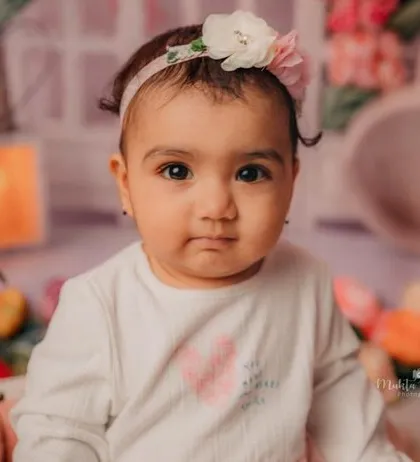 This 8-month-old beauty is looking right at the camera, ready for her close-up in a garden of flowers.