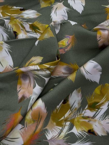 A unique feather print on our olive green rayon satin. This fabric combines a soft, silky feel with an artistic design, perfect for a standout blouse or dress.