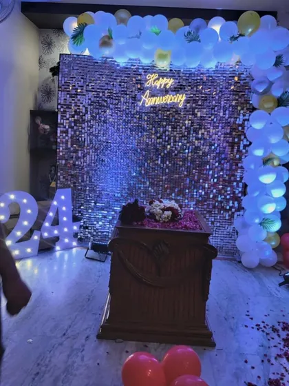A 24th-anniversary party with a shimmering sequin wall. The setup includes a simple balloon frame, a neon sign, and light-up numbers, creating a cool, club-like atmosphere.