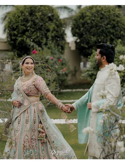 A candid moment of the couple walking hand-in-hand through a lush garden, their smiles reflecting their happiness.
