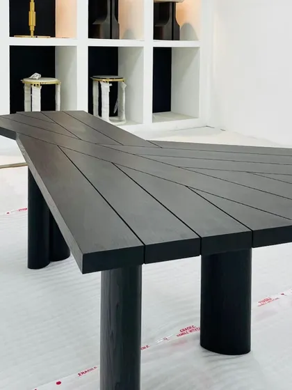 This funky table, crafted from teak wood with a black finish, can serve as a statement piece or a unique center table. The top is composed of angled planks, creating a dynamic, geometric surface.
