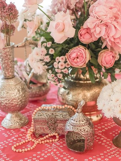 The table decor featured intricate details, including silver artifacts and pearl strings, set against a vibrant pink bandhani-print tablecloth.