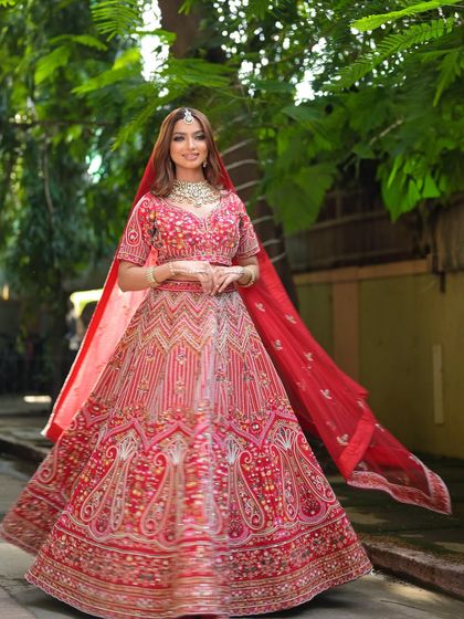 A full-length shot of a bride in a magnificent red lehenga, perfect for capturing those grand, cinematic wedding photos. My rental collection focuses on providing these unforgettable looks.