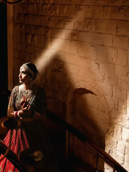 A creative bridal portrait using a sliver of light to highlight the bride's profile against a textured wall, creating a sense of mystery and elegance.