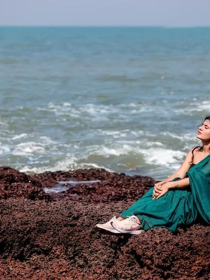 A moment of peace and connection with nature, as the model sits on the rocks and soaks in the ocean view.