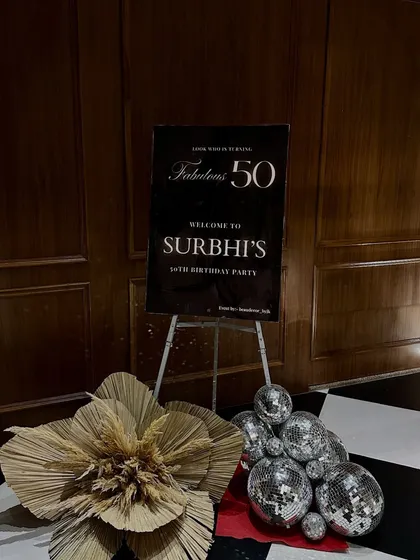 The welcome sign for a "Fabulous 50" birthday party. We set the disco theme right from the entrance with a stylish sign, disco balls, and a large dried palm leaf accent.