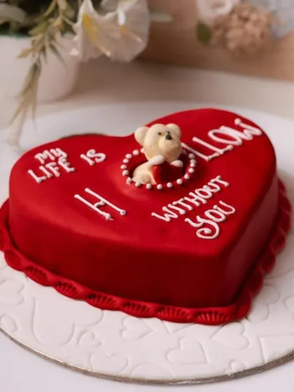 A playful and romantic Valentine's cake with the message "My life is hollow without you," featuring a cute teddy bear peeking out from the center.