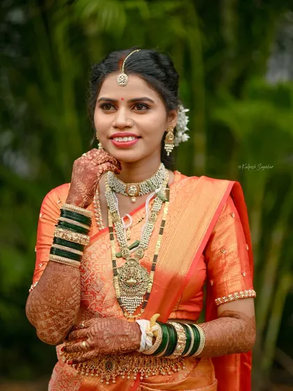 A stunning Maharashtrian bride in a traditional orange silk saree. For bridal draping, I ensure the saree is secure and comfortable, allowing the bride to enjoy her special day without any worries.
