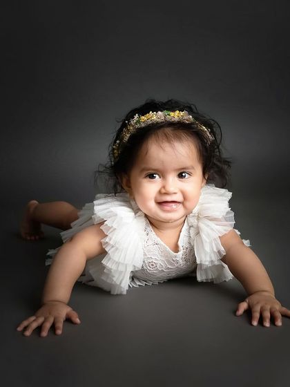To the cutest of smiles. This little girl crawling towards the camera on a simple grey backdrop is a perfect example of a classic, personality-filled milestone photo.