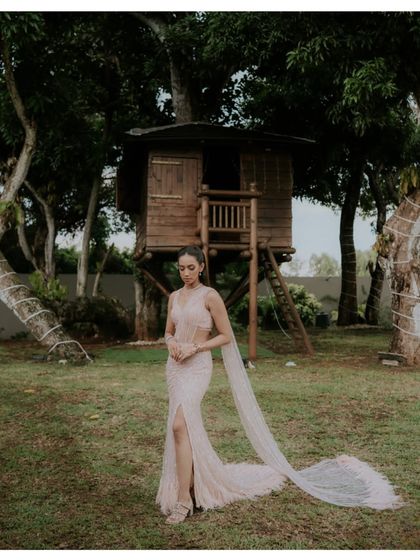 A solo portrait of the bride in her stunning gown, featured in Brides Today. The long, flowing train and the unique treehouse setting in Mauritius create a modern fairytale image.