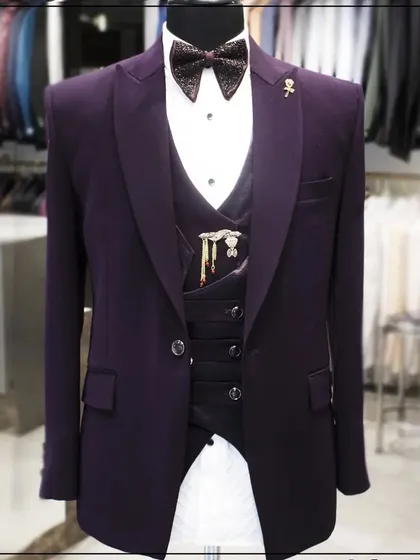 A deep purple three-piece tuxedo with a unique vest and lapel pins. This shows how we can accessorize a suit to reflect your personal style.