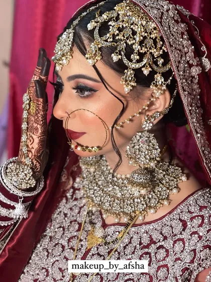 A stunning side profile showcasing the intricate Hyderabadi jhoomar and matha patti. The makeup is bold with a deep red lip and dramatic eyes.