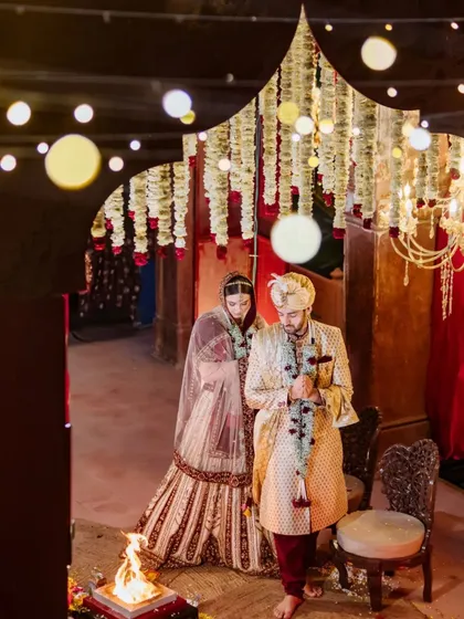 A high-angle shot of the couple during their pheras around the sacred fire, with the mandap beautifully lit by string lights.