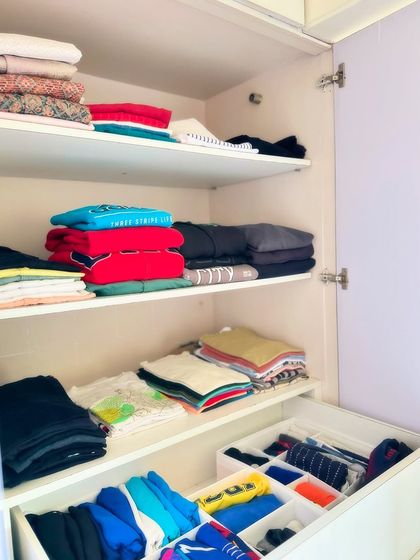 This men's wardrobe shelf shows how we stack folded items like sweaters and t-shirts neatly, with smaller items like socks organized in drawer bins below.