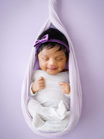 A smile in their sleep is one of the most precious moments to capture. This little one, nestled in a lavender sling, gave us the sweetest sleepy grin during her newborn session.