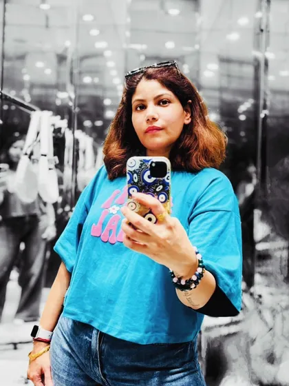 A mirror selfie with a cool, reflective background, wearing a blue graphic tee.