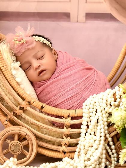 A close-up shot of the baby in the pink vintage pram setup, focusing on her peaceful expression and delicate features.