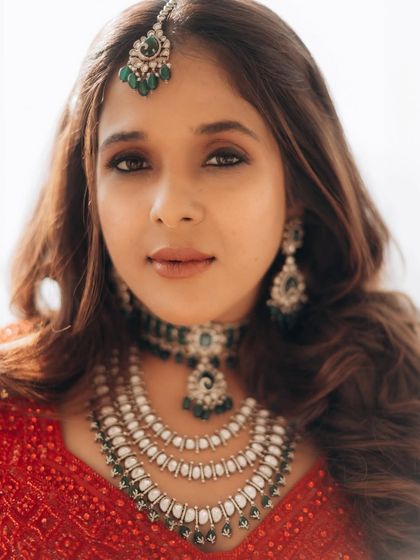 A classic, brightly lit bridal portrait. This shot beautifully showcases her makeup, jewelry, and the vibrant color of her wedding attire.