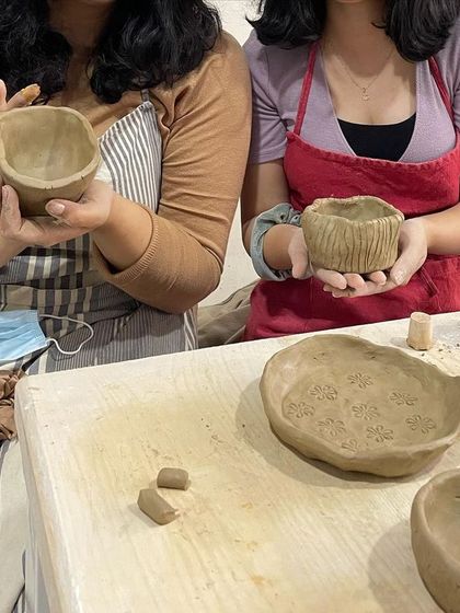 Two students proudly show off the bowls they've just made using the pinch pot technique.