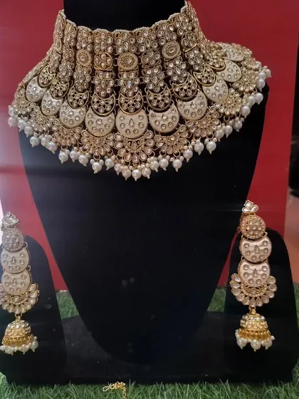 A white and gold choker set with a unique half-moon 'chand' design and matching jhumkas.